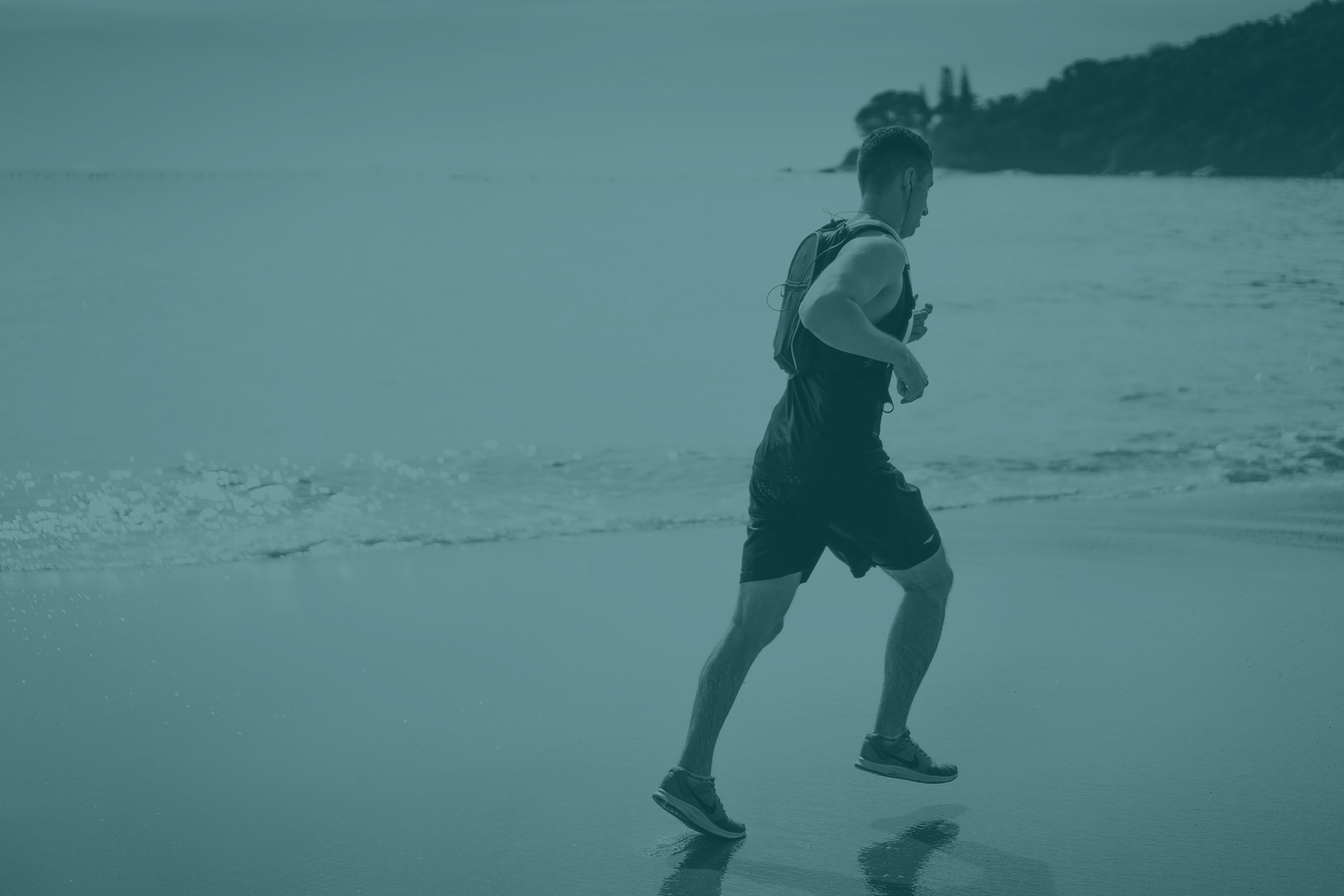 a man faces away from the camera running down the beach